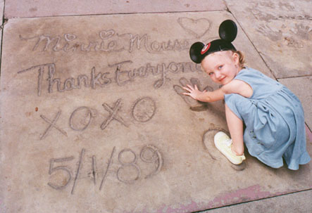 Autumn puts her hands and feet in Minnie's handprints and footprints
